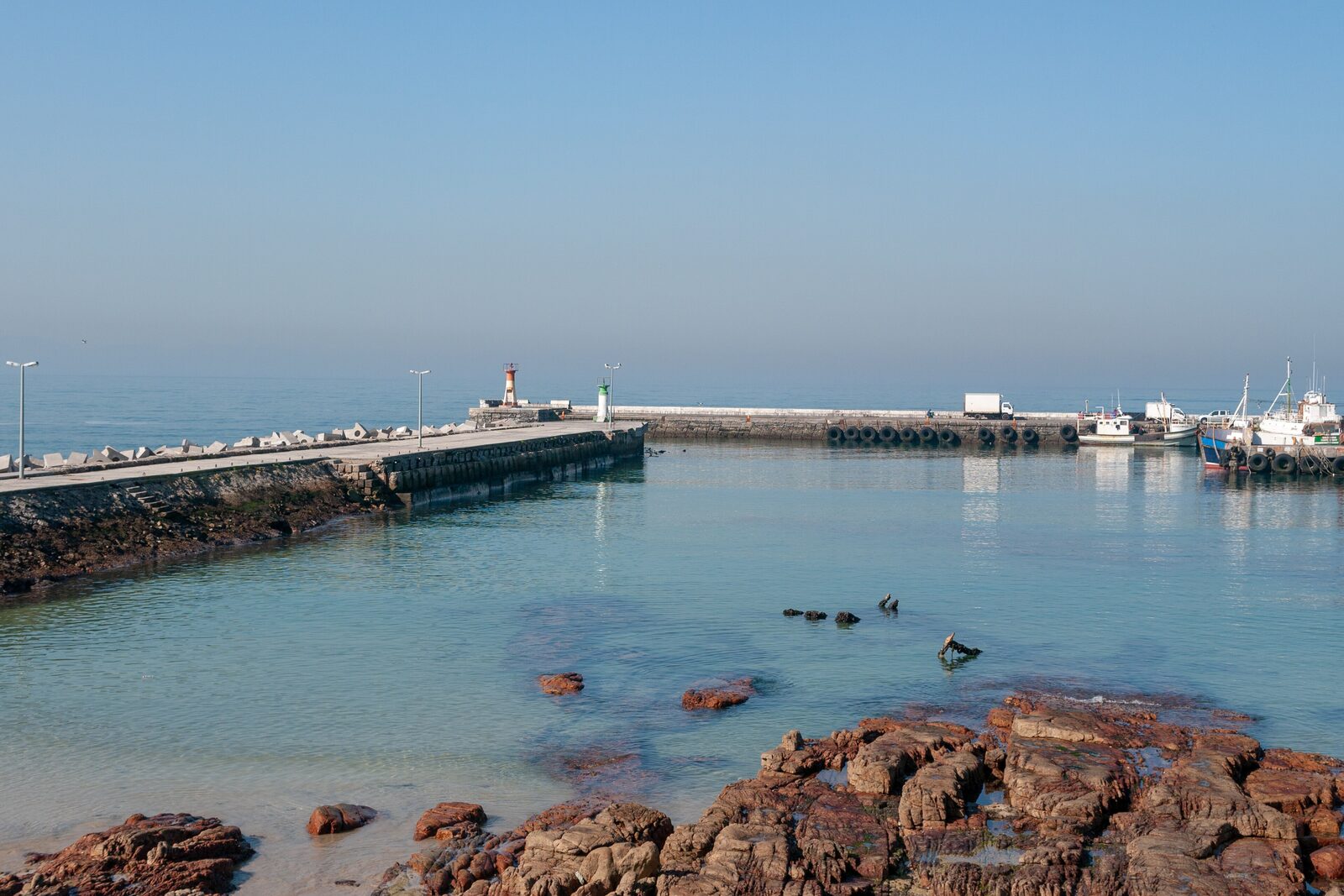 Colourful fishing boats in Kalk Bay harbour with mountains behind