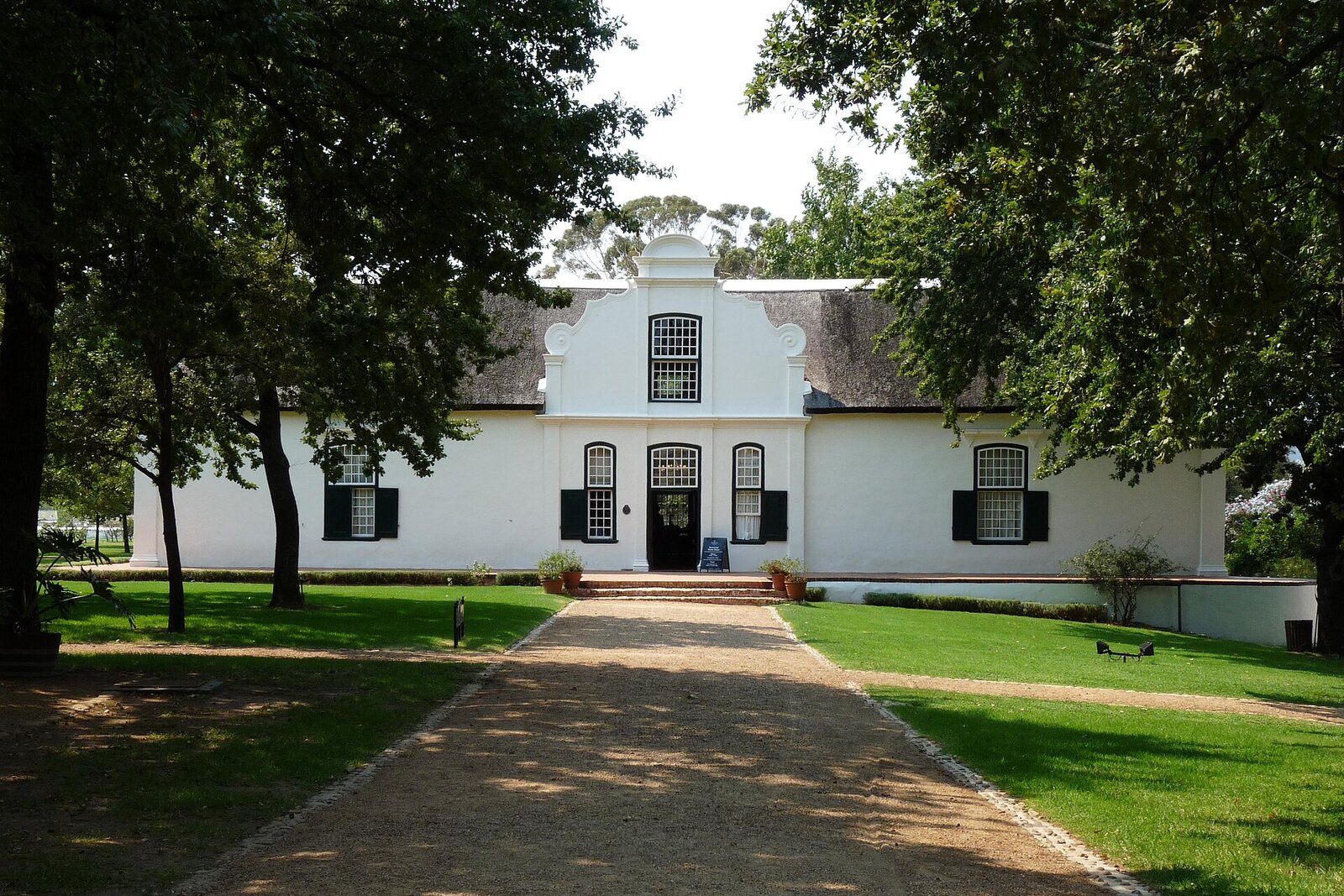 A whitewashed Cape Dutch manor house surrounded by vineyards near Stellenbosch